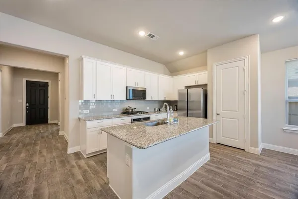 a large kitchen with a center island and stainless steel appliances