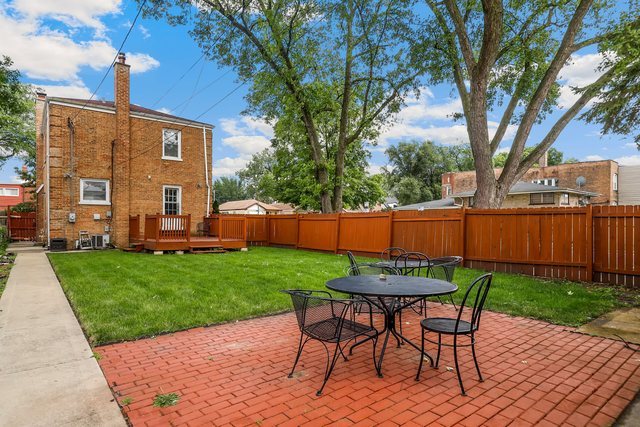 8458 South Constance Avenue Chicago, IL 60617 - Photo 22 of 23 a view of a backyard with table and chairs potted plants and a large tree