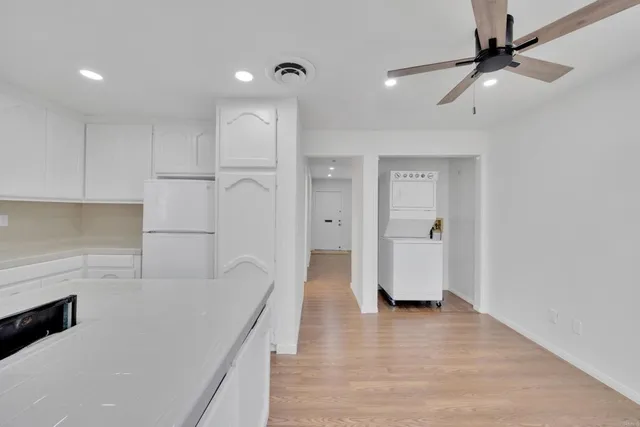 an empty room with wooden floor ceiling fan and windows