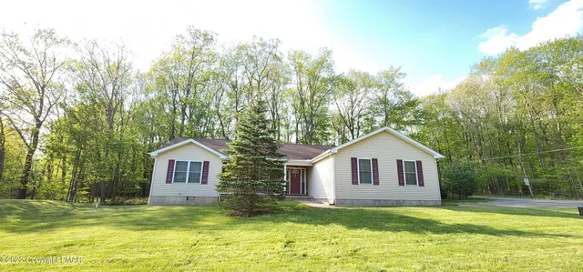 a view of a house with a yard and large trees