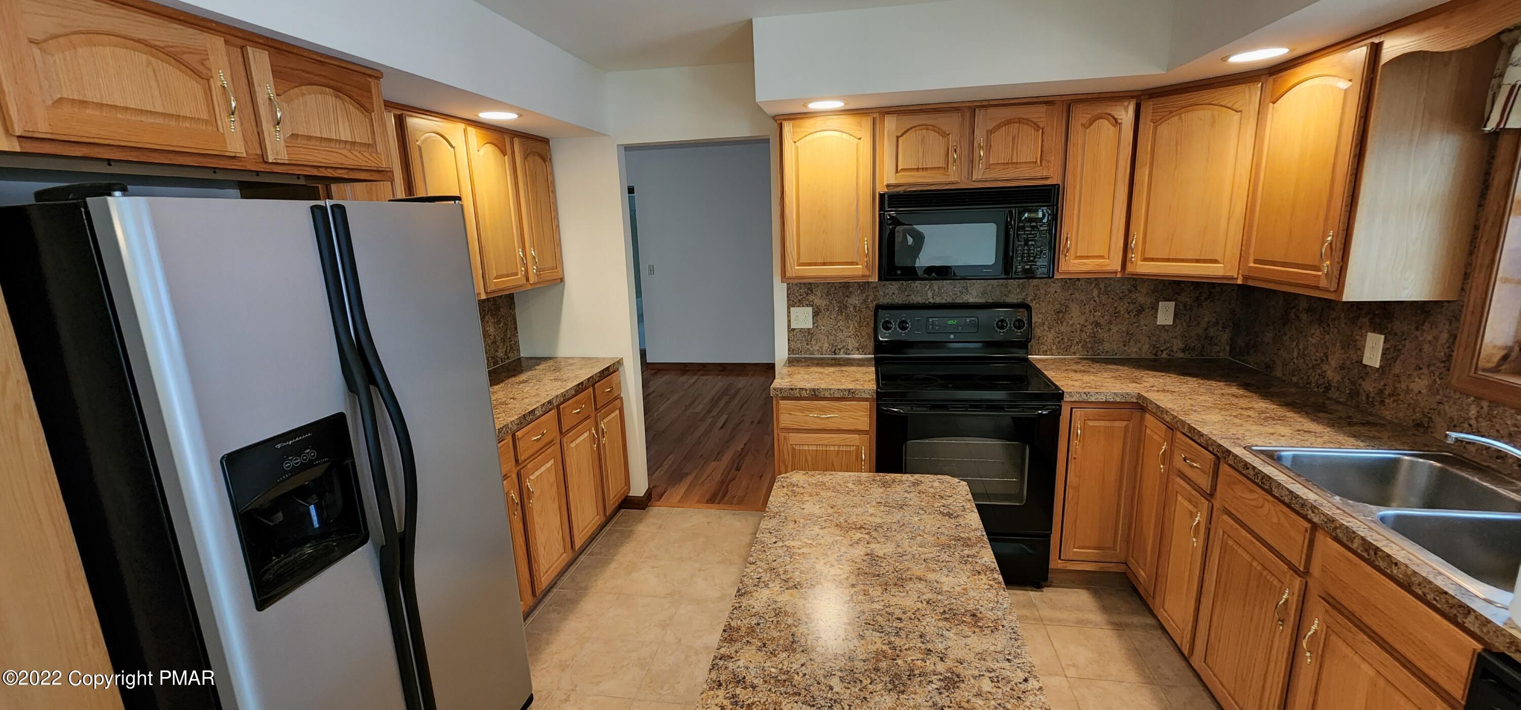 203 Sutton Place Pocono Summit, PA 18346 - Photo 7 of 22 a kitchen with sink a refrigerator and cabinets