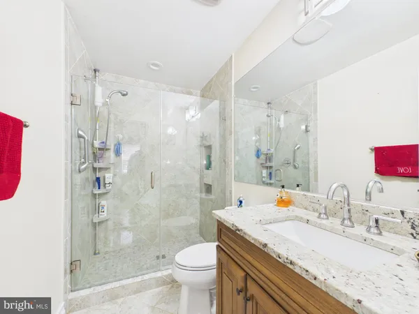 a bathroom with a granite countertop sink toilet mirror and shower