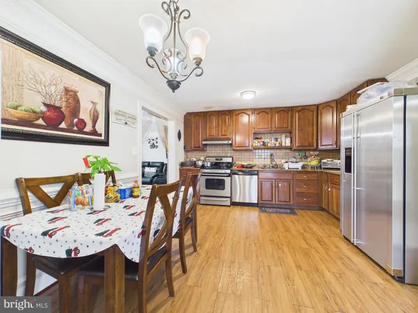 a kitchen with stainless steel appliances granite countertop a refrigerator a stove top oven a sink dishwasher and white cabinets with wooden floor