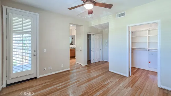 a view of empty room with wooden floor and fan
