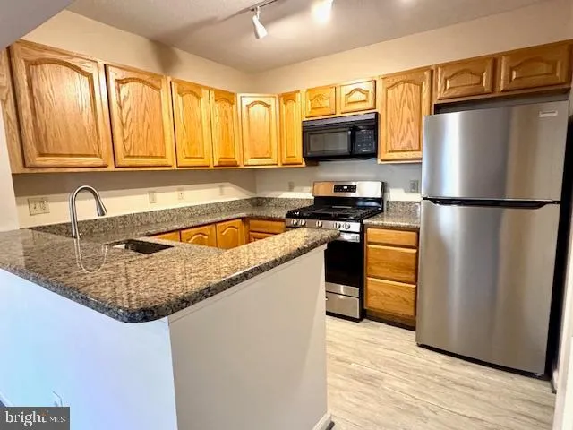 a kitchen with granite countertop a sink a stove and cabinets