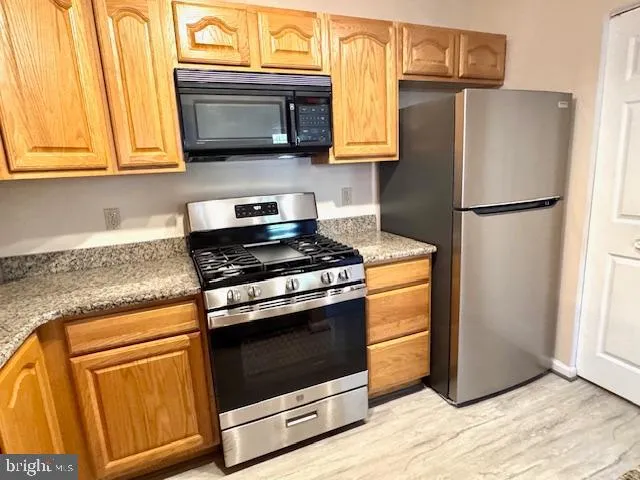 a kitchen with stainless steel appliances granite countertop a sink and a refrigerator