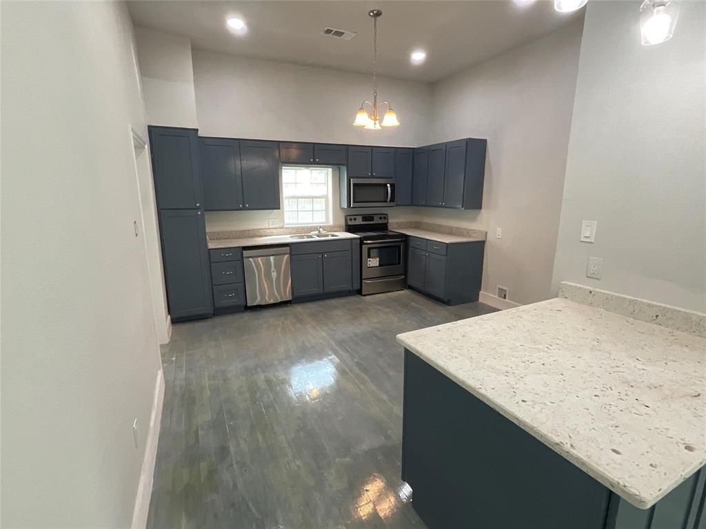 207 College Street Chico, TX 76431 - Photo 11 of 20 Kitchen with appliances with stainless steel finishes, a chandelier, hanging light fixtures, dark wood finished floors, and recessed lighting