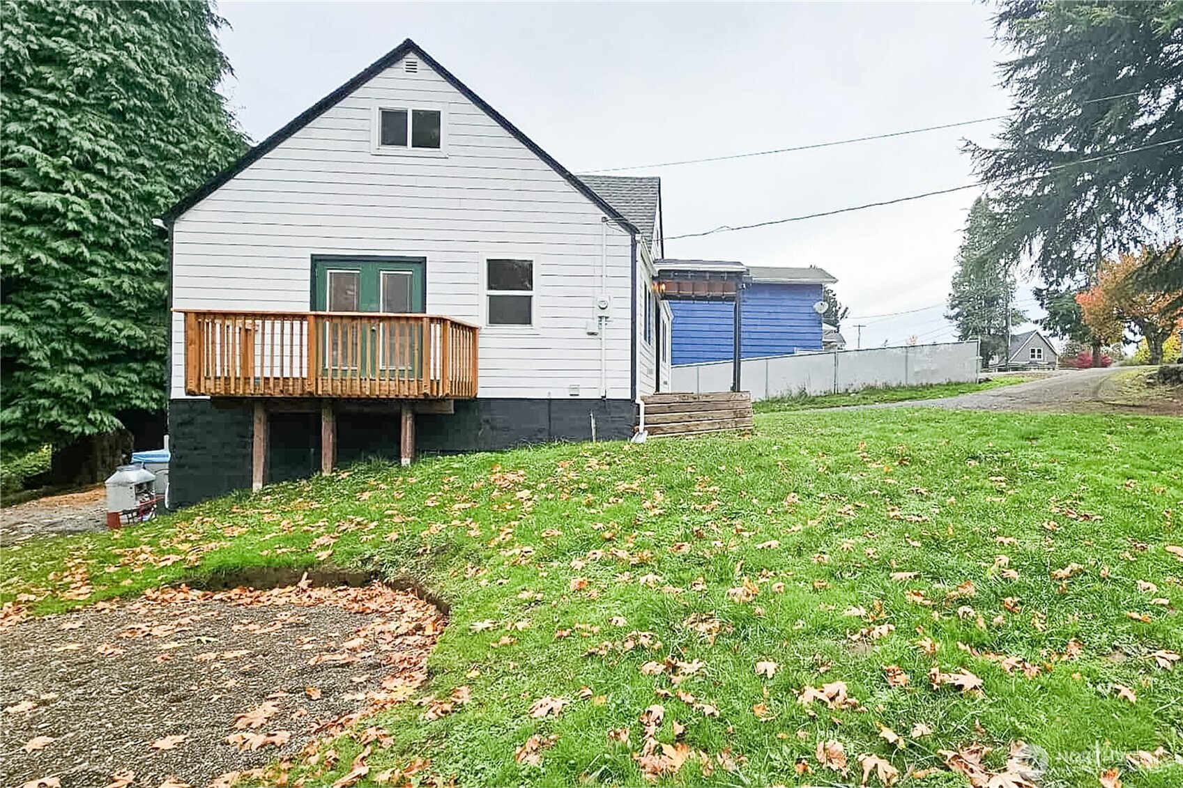 312 Nevada Drive Longview, WA 98632 - Photo 25 of 27 a white house that has a small yard and large trees with wooden fence