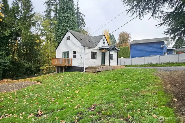 a view of a house with a big yard potted plants and large tree