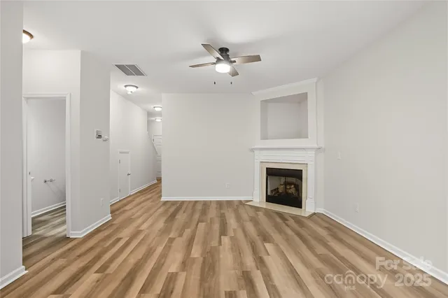 a view of empty room with fireplace and wooden floor