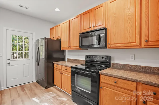a kitchen with granite countertop wooden cabinets stainless steel appliances and a window