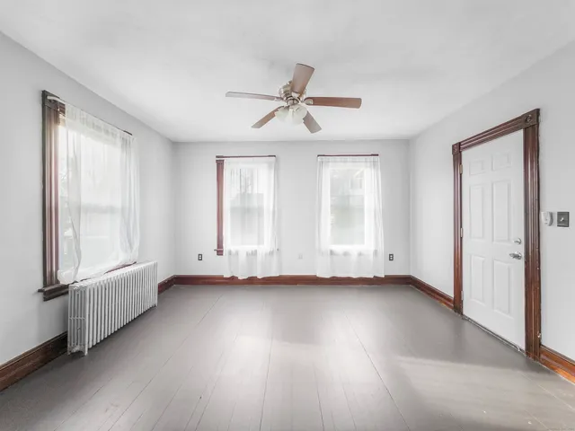 a view of an empty room with a window and wooden floor