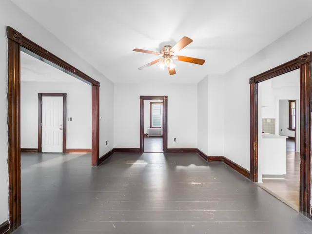 a view of an empty room with window and wooden floor