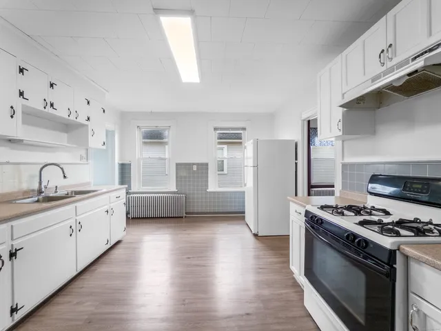 a kitchen with granite countertop a sink stove and refrigerator