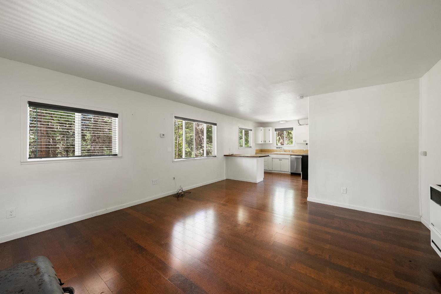 6420 Starkes Grade Road Pollock Pines, CA 95726 - Photo 24 of 58 a view of a kitchen and an empty room with wooden floor and windows