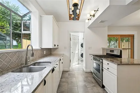 a kitchen with stainless steel appliances granite countertop a sink a stove and a refrigerator