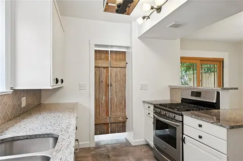 a kitchen with granite countertop a sink stove and cabinets
