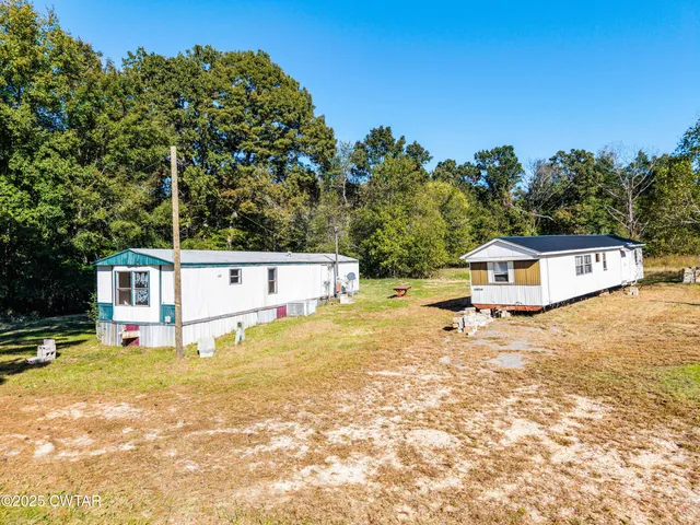 a white house with a yard and large trees