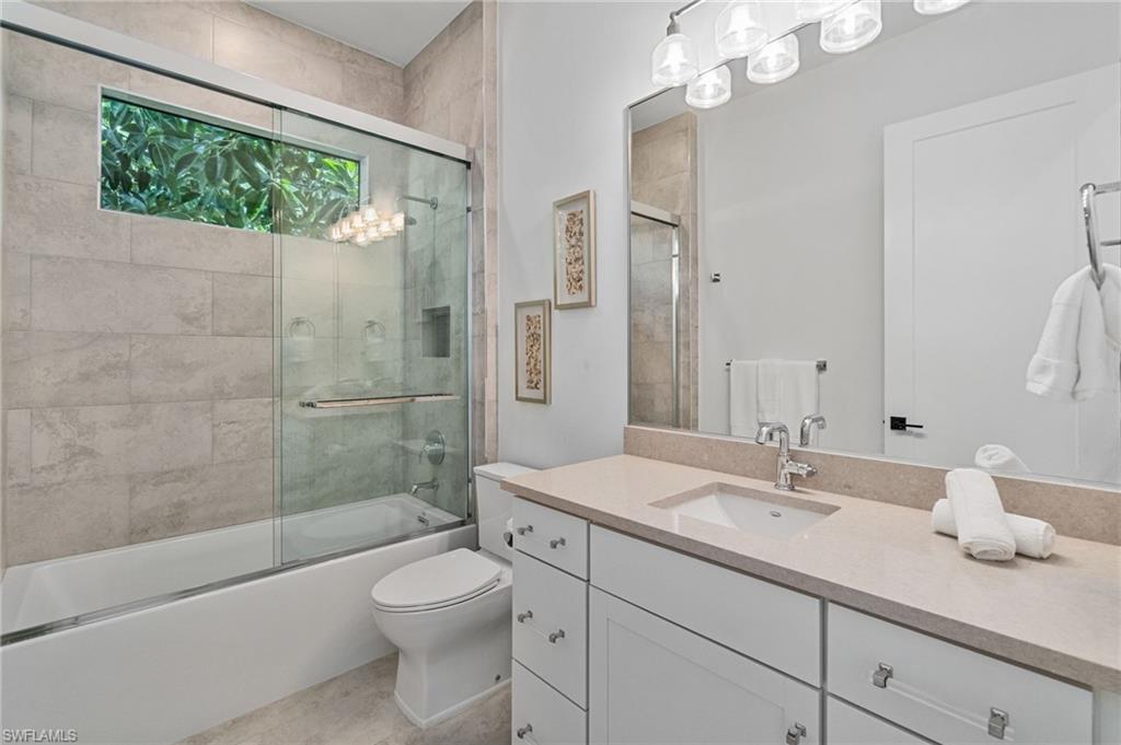 803 96th Avenue North Naples, FL 34108 - Photo 37 of 50 a bathroom with a granite countertop sink a toilet a mirror and shower
