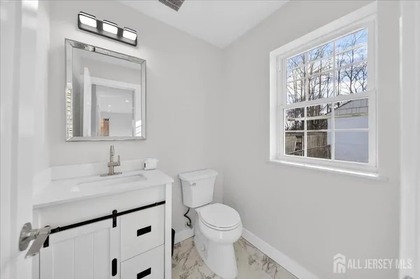 a bathroom with a toilet a sink a mirror and a window
