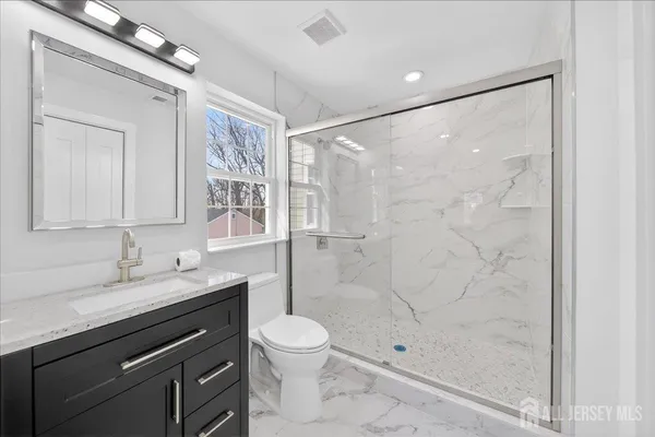 a bathroom with a granite countertop sink toilet and shower
