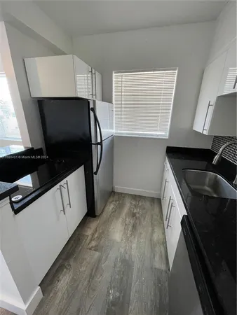 a kitchen with granite countertop a stove a microwave a sink and cabinets