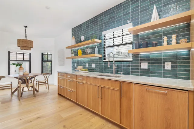 a living room with stainless steel appliances granite countertop a dining table chairs and a large window