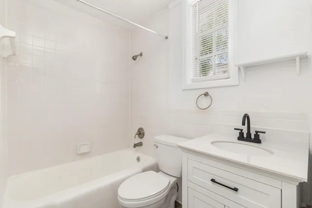 a bathroom with a bathtub shower sink vanity mirror and toilet