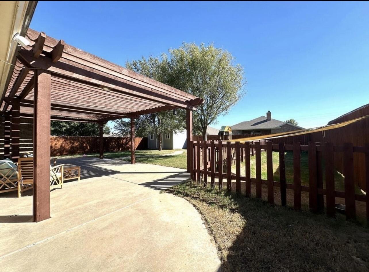 5513 104th Street Lubbock, TX 79424 - Photo 2 of 3 a view of a patio with a table and chairs under an umbrella with wooden fence