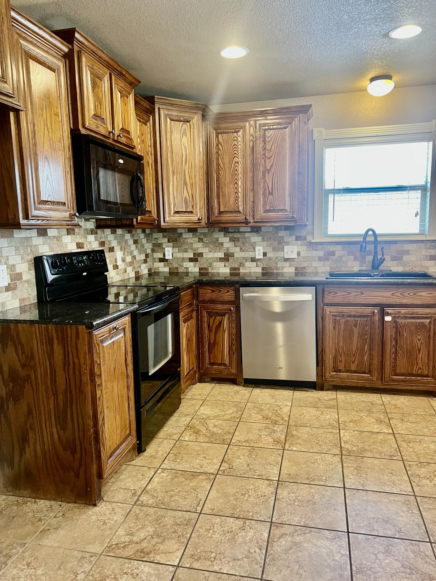 5513 104th Street Lubbock, TX 79424 - Photo 6 of 10 a large kitchen with granite countertop a stove top oven microwave and cabinets