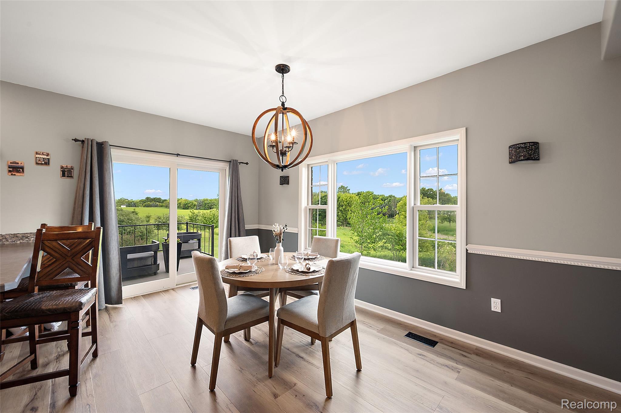 5035 Hidden Ridge Road Metamora, MI 48455 - Photo 17 of 65 Dining area featuring wood-finish flooring, a contemporary chandelier, two-tone walls with chair rail molding, and a sliding glass door to a balcony