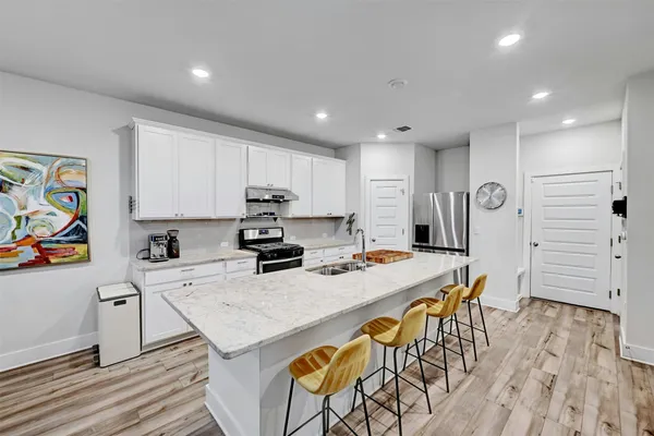 a kitchen with stainless steel appliances granite countertop a table chairs sink refrigerator and microwave