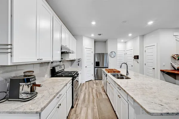 a kitchen with stainless steel appliances granite countertop counter space a sink a stove and a wooden floors