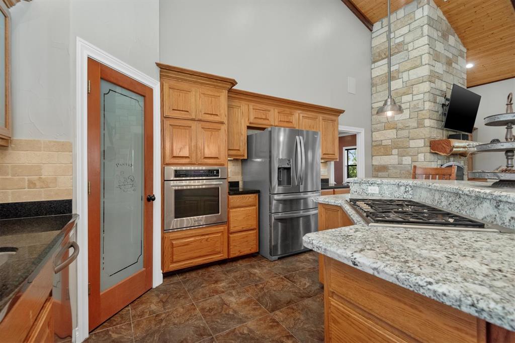 3759 Cr 126 Road Bedias, TX 77831 - Photo 10 of 38 a kitchen with stainless steel appliances granite countertop a refrigerator a stove and a sink with wooden cabinets