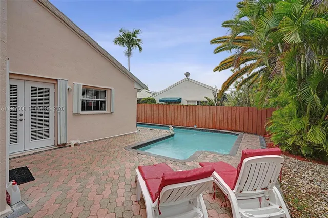 a patio with table and chairs and potted plants