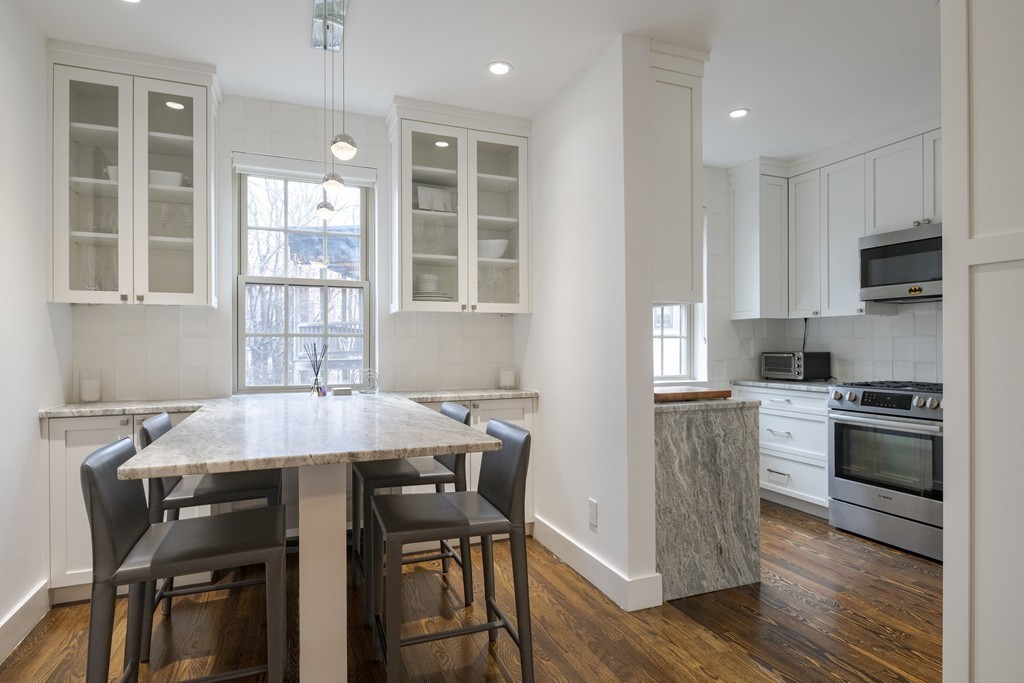 1490 Beacon Street, Unit 4 Brookline, MA 02446 - Photo 6 of 26 a kitchen with a table chairs stove and cabinets