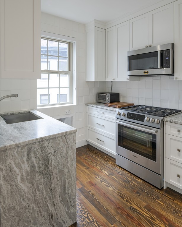 1490 Beacon Street, Unit 4 Brookline, MA 02446 - Photo 7 of 26 a kitchen with stainless steel appliances a stove a microwave and cabinets