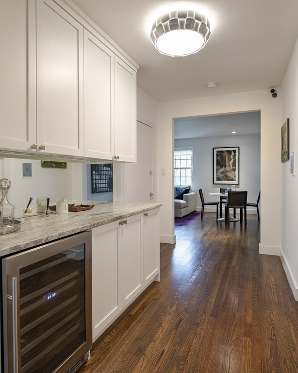 1490 Beacon Street, Unit 4 Brookline, MA 02446 - Photo 9 of 26 a kitchen with granite countertop a stove a sink and white cabinets with wooden floor next to windows
