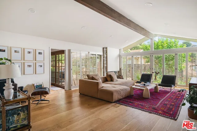 a living room with furniture large windows and wooden floor