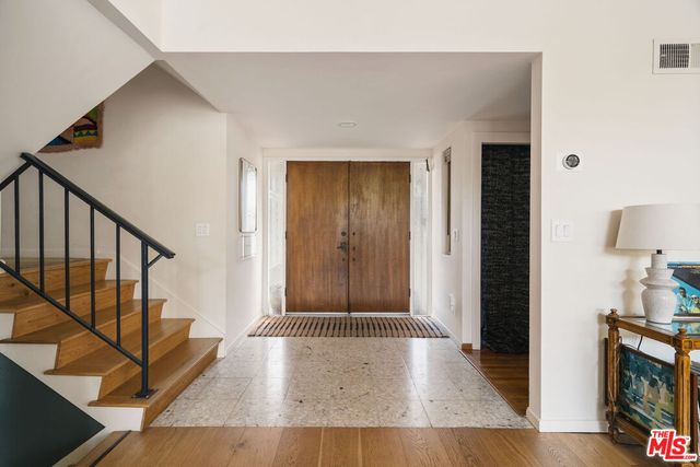 a kitchen with stainless steel appliances granite countertop a refrigerator a sink dishwasher a stove and a dining table with wooden floor