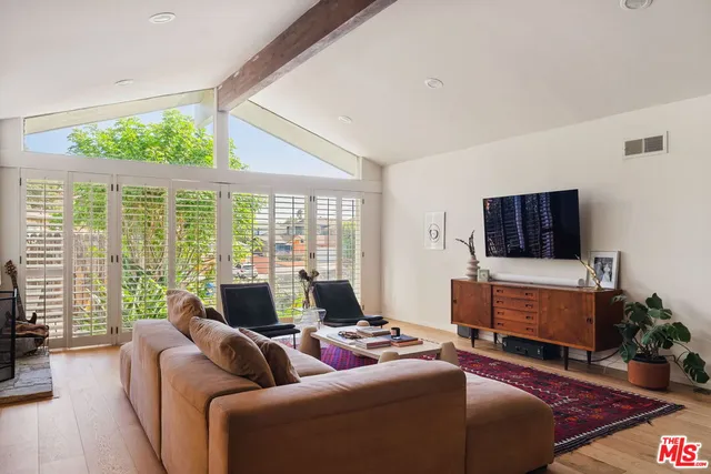 a living room with furniture a flat screen tv and a floor to ceiling window
