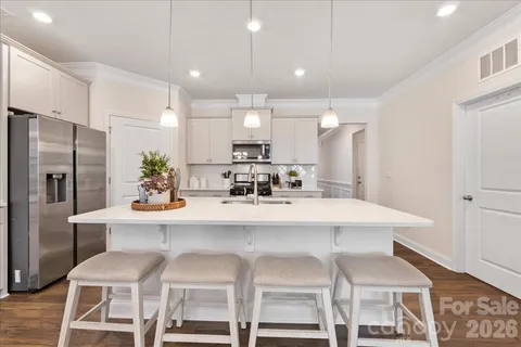 a kitchen with stainless steel appliances granite countertop a sink a stove a refrigerator and white cabinets with wooden floor