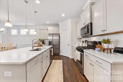 a kitchen with stainless steel appliances granite countertop a sink stove refrigerator and cabinets