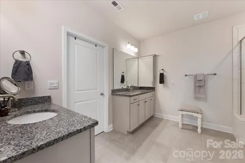 a en suite bathroom with a granite countertop sink and a mirror