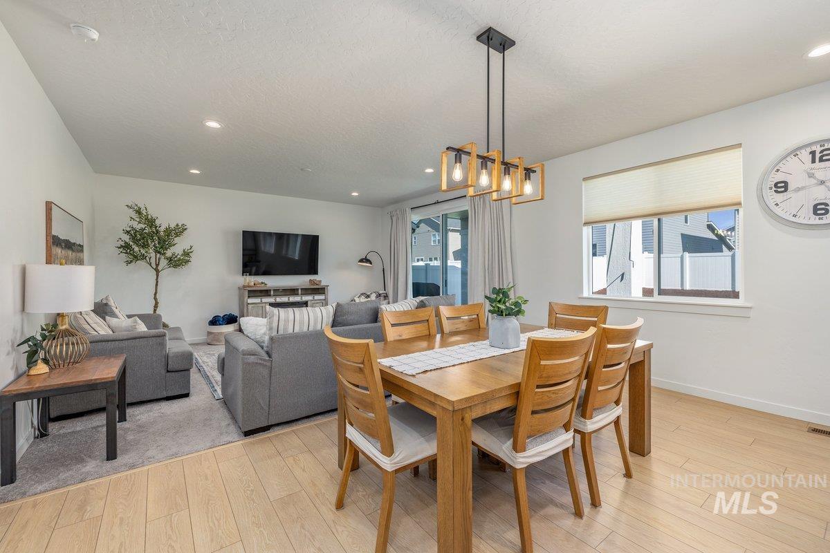 1380 West Chilitna Street Meridian, ID 83642 - Photo 16 of 50 Open-concept dining area featuring wood-finish flooring, a contemporary linear chandelier with exposed bulbs, and a spacious window