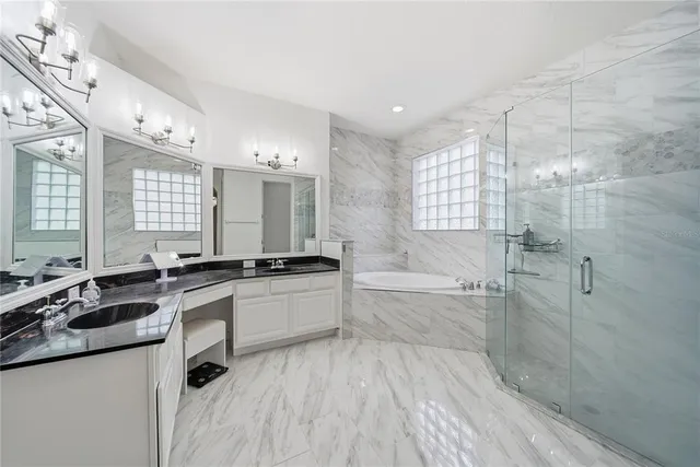 a large white bathroom with a granite countertop sink a toilet a mirror and shower