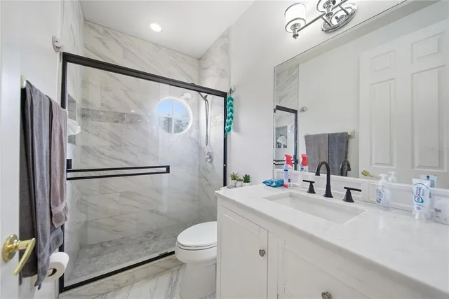 a bathroom with a shower sink vanity mirror and toilet