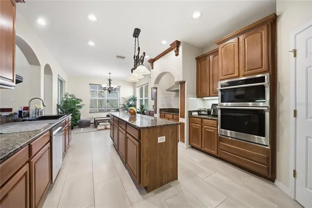 a kitchen with stainless steel appliances kitchen island granite countertop a stove and a sink