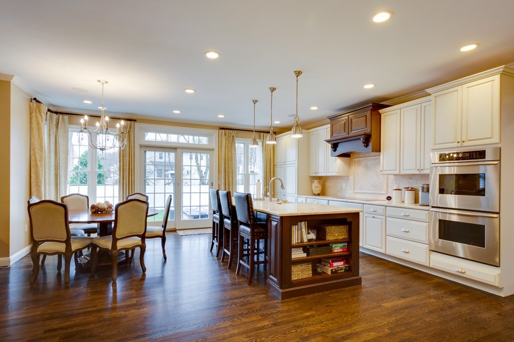 24 Fletcher Road Needham, MA 02492 - Photo 9 of 29 a open kitchen with stainless steel appliances granite countertop a stove top oven a dining table and chairs with wooden floor