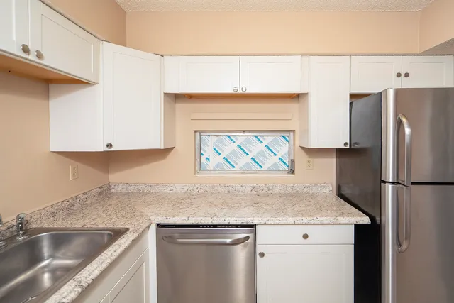 a kitchen with a sink a refrigerator and cabinets